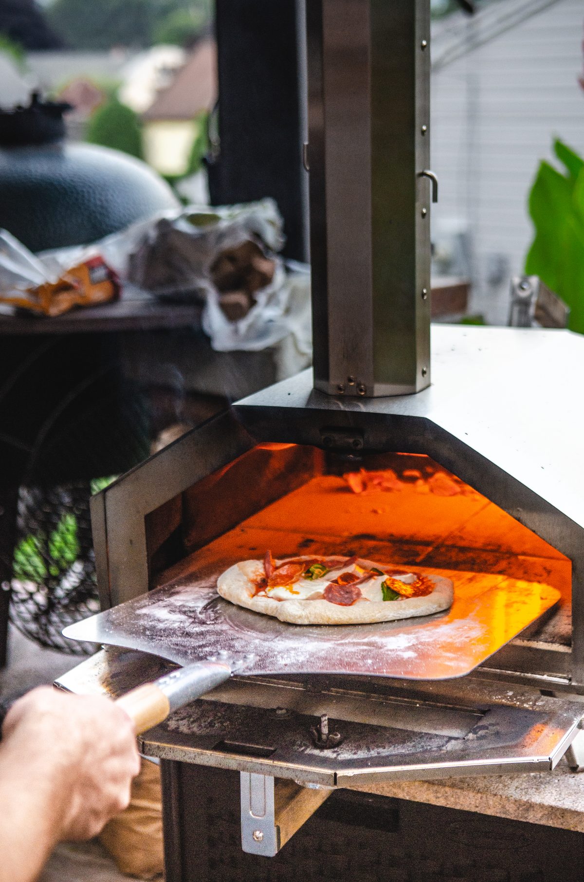 Wood-fired pizza coming off the grill